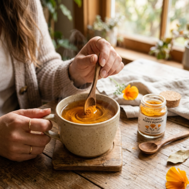 California poppy powder being stirred into a warm mug, with a spoon and open jar in soft focus behind it